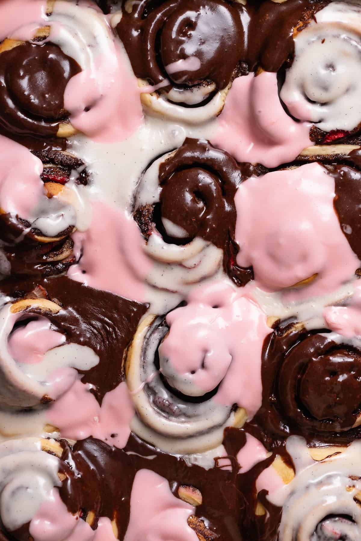 Neapolitan cinnamon rolls with pink, brown, and white marbled frosting.