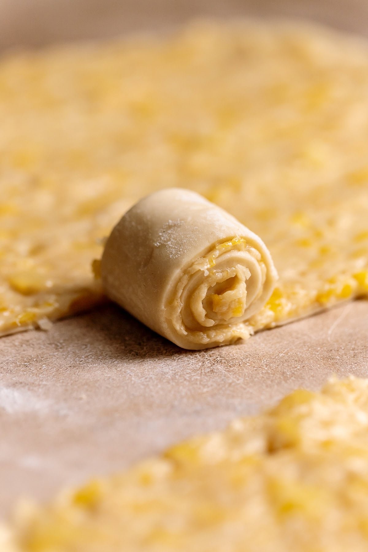 A strip of dough being rolled up into a cinnamon roll.