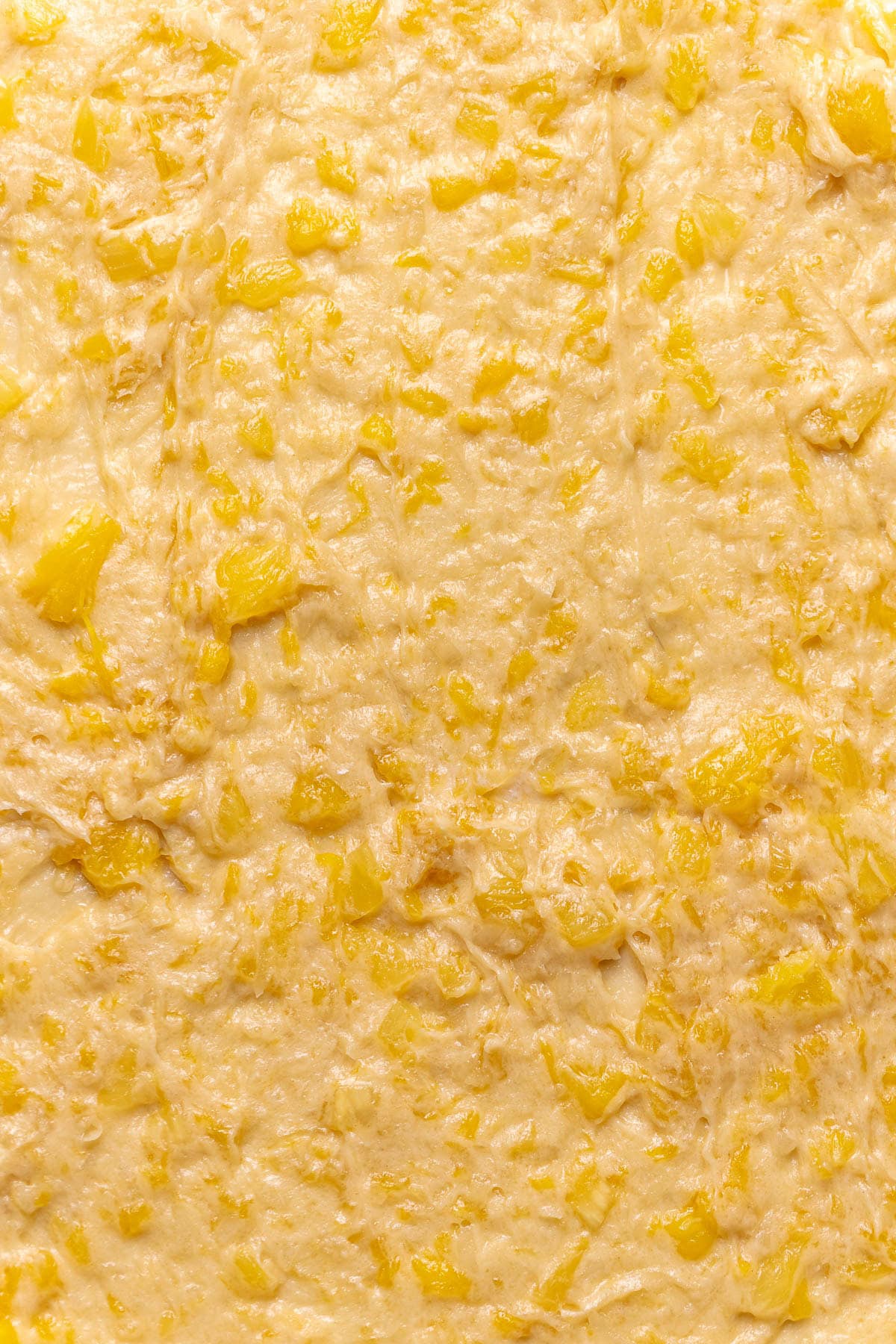Pineapple coconut filling spread out onto rolled out cinnamon roll dough.