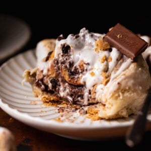 A smores roll on a white plate with bites missing to show the gooey texture.
