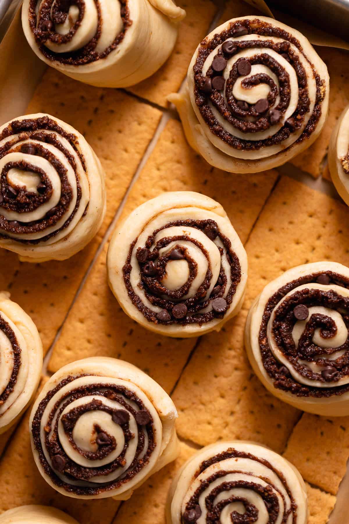S'mores cinnamon rolls in a baking pan sitting on top of graham cracker sheets.