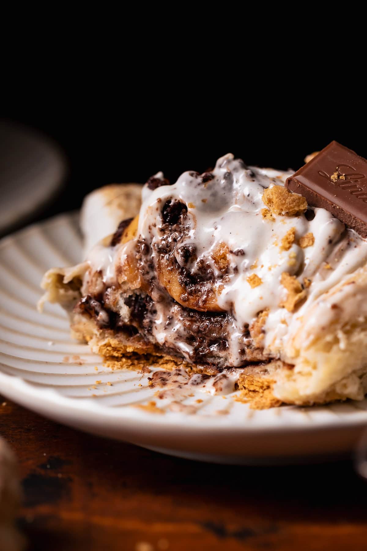 A smores roll on a white plate with bites missing to show the gooey texture.