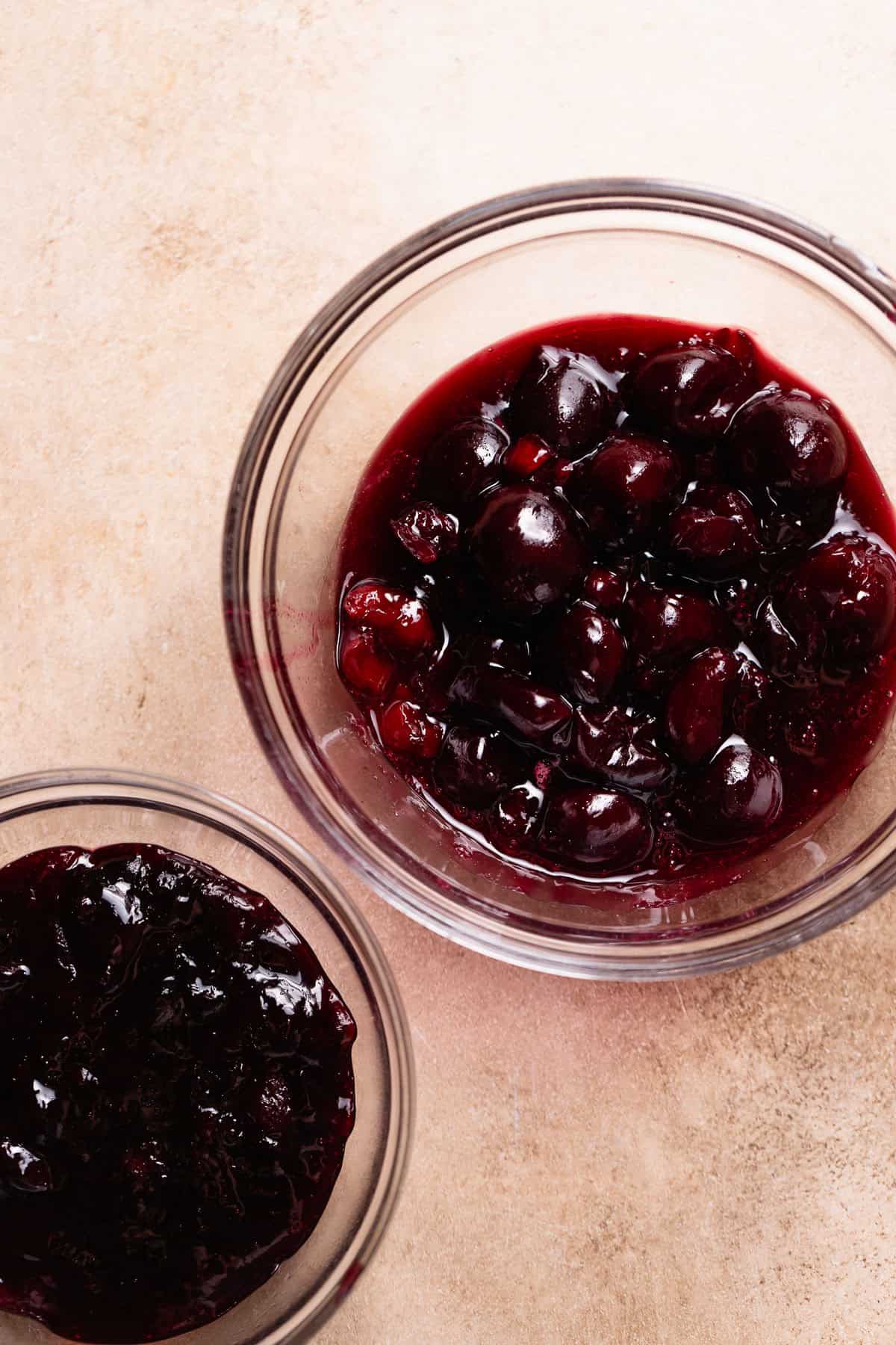 Two small bowls showing homemade cherry jam and cooked whole cherries for the cinnamon roll filling.