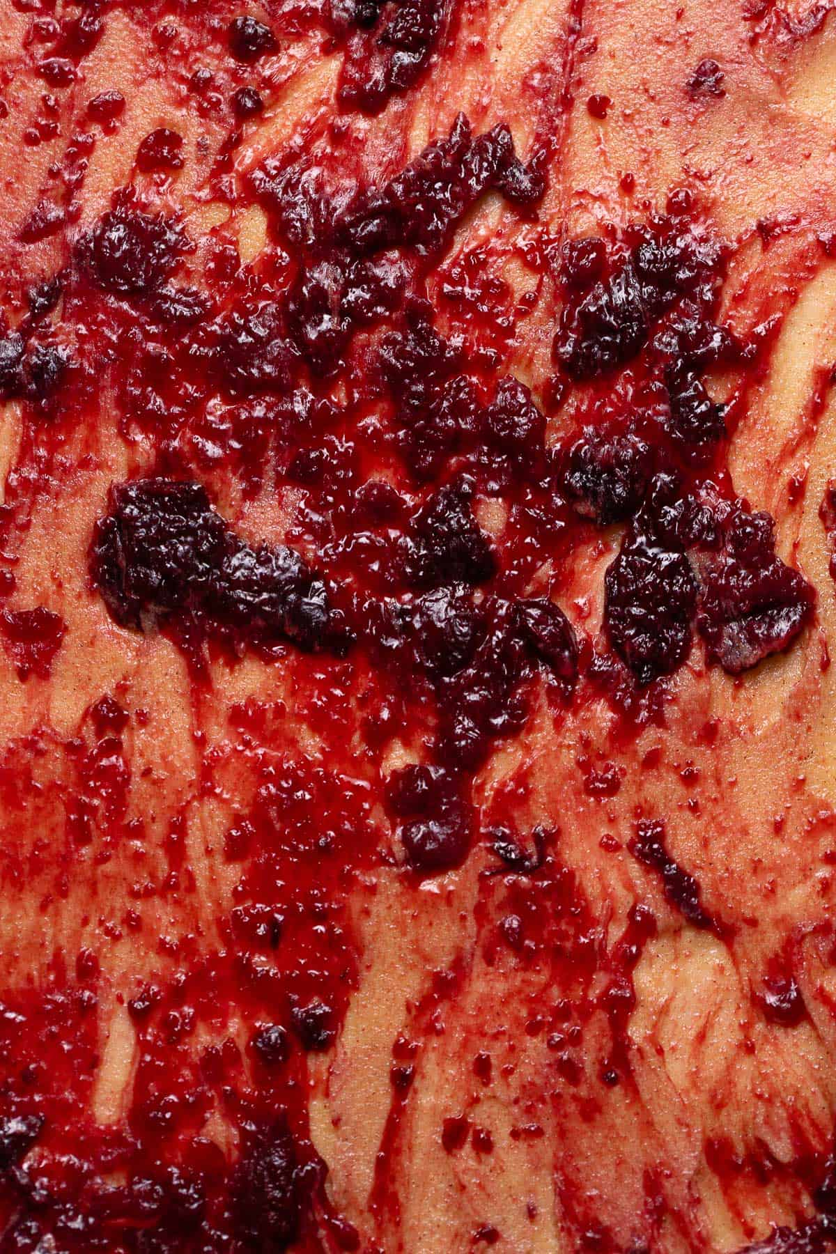 Cherry pie jam spread over the surface of the cinnamon roll dough.
