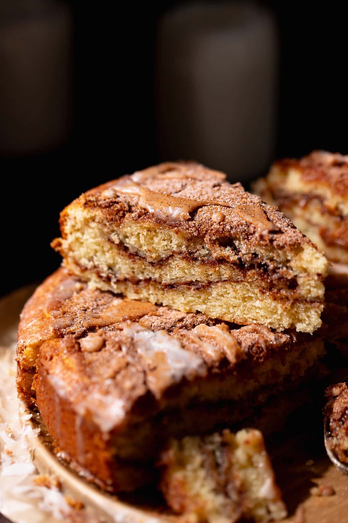 A slice of cinnamon coffee cake stacked on top of others to show the brown sugar cinnamon swirls.