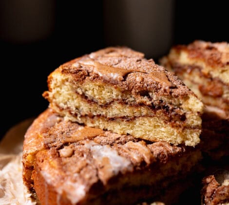 A slice of cinnamon swirl coffee cake stacked on top of other slices of cake.