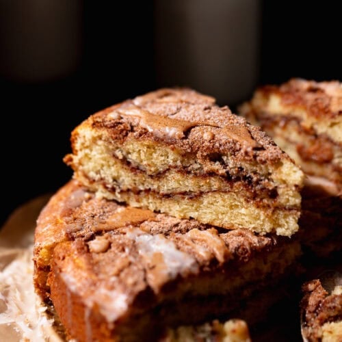A slice of cinnamon swirl coffee cake stacked on top of other slices of cake.