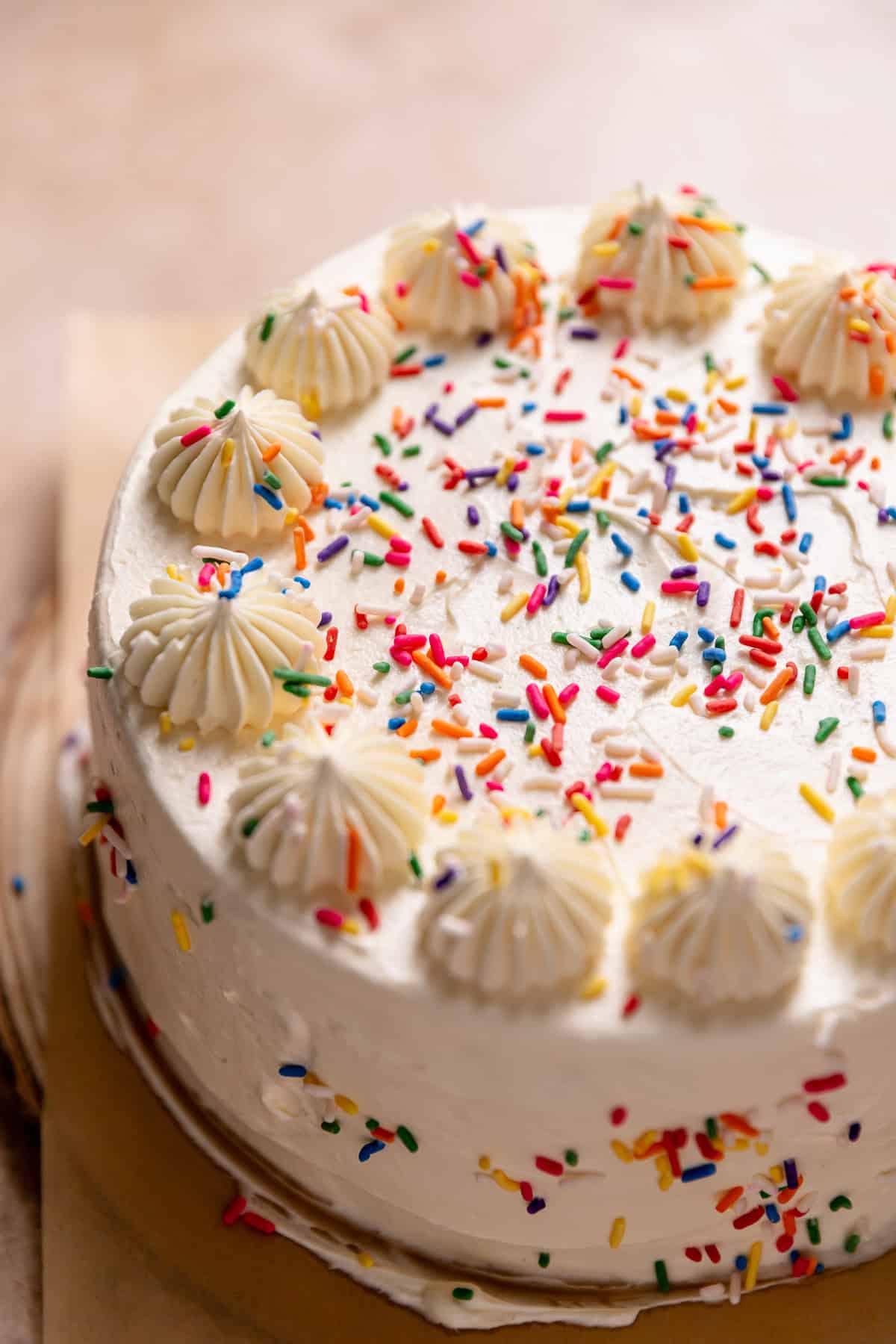 White sprinkle cake with dollops of buttercream on top.
