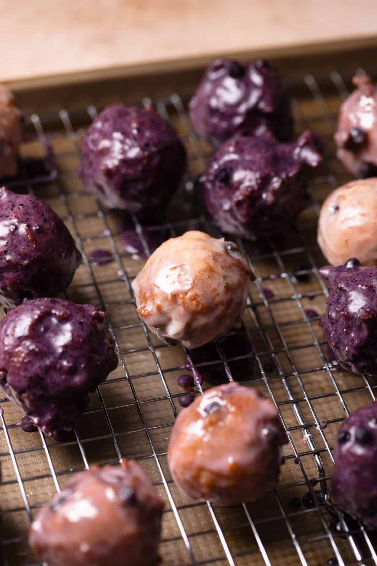 Mini blueberry glazed cake donuts on a wire rack tray.