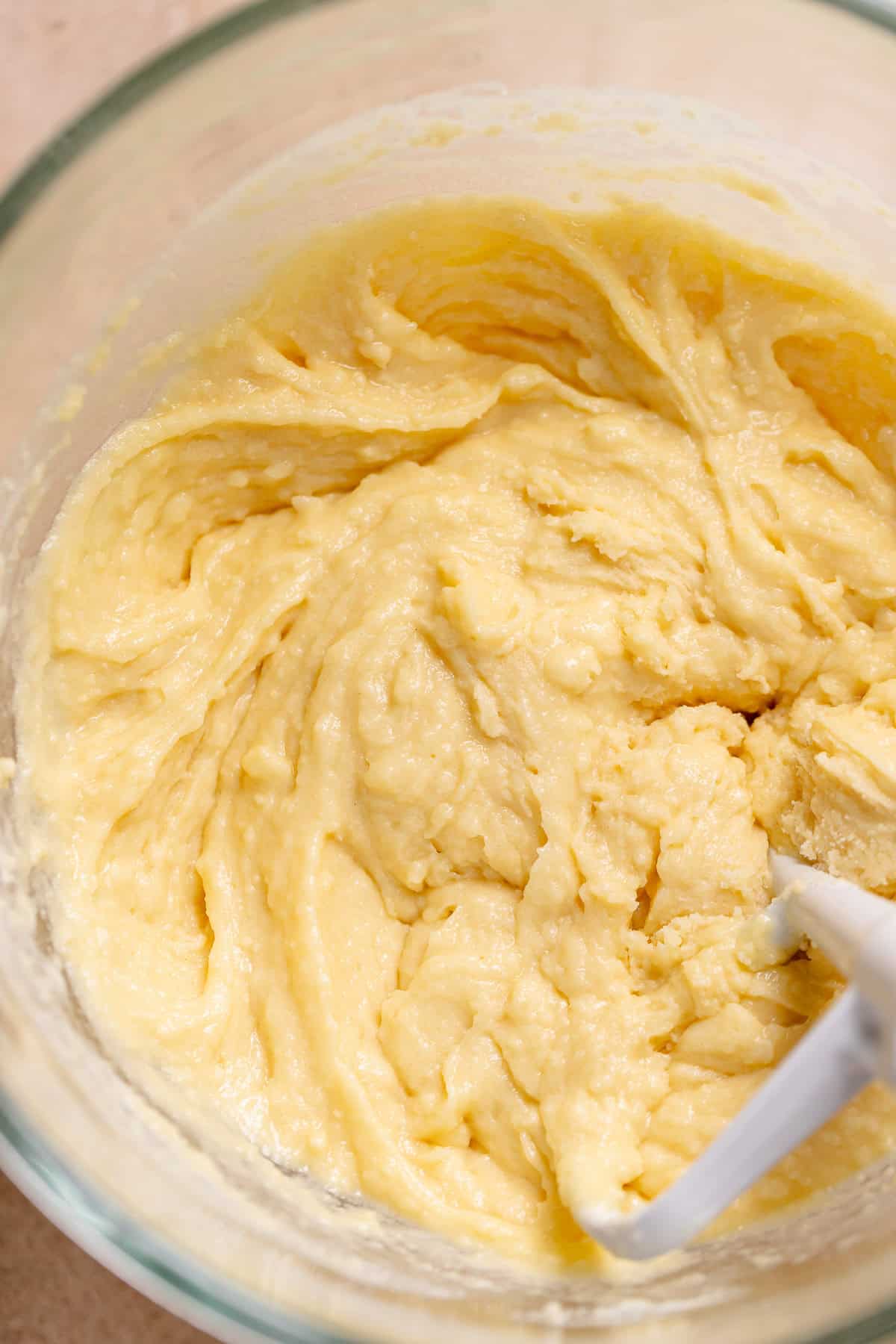White cake batter in a stand mixer bowl mixed to a paste.