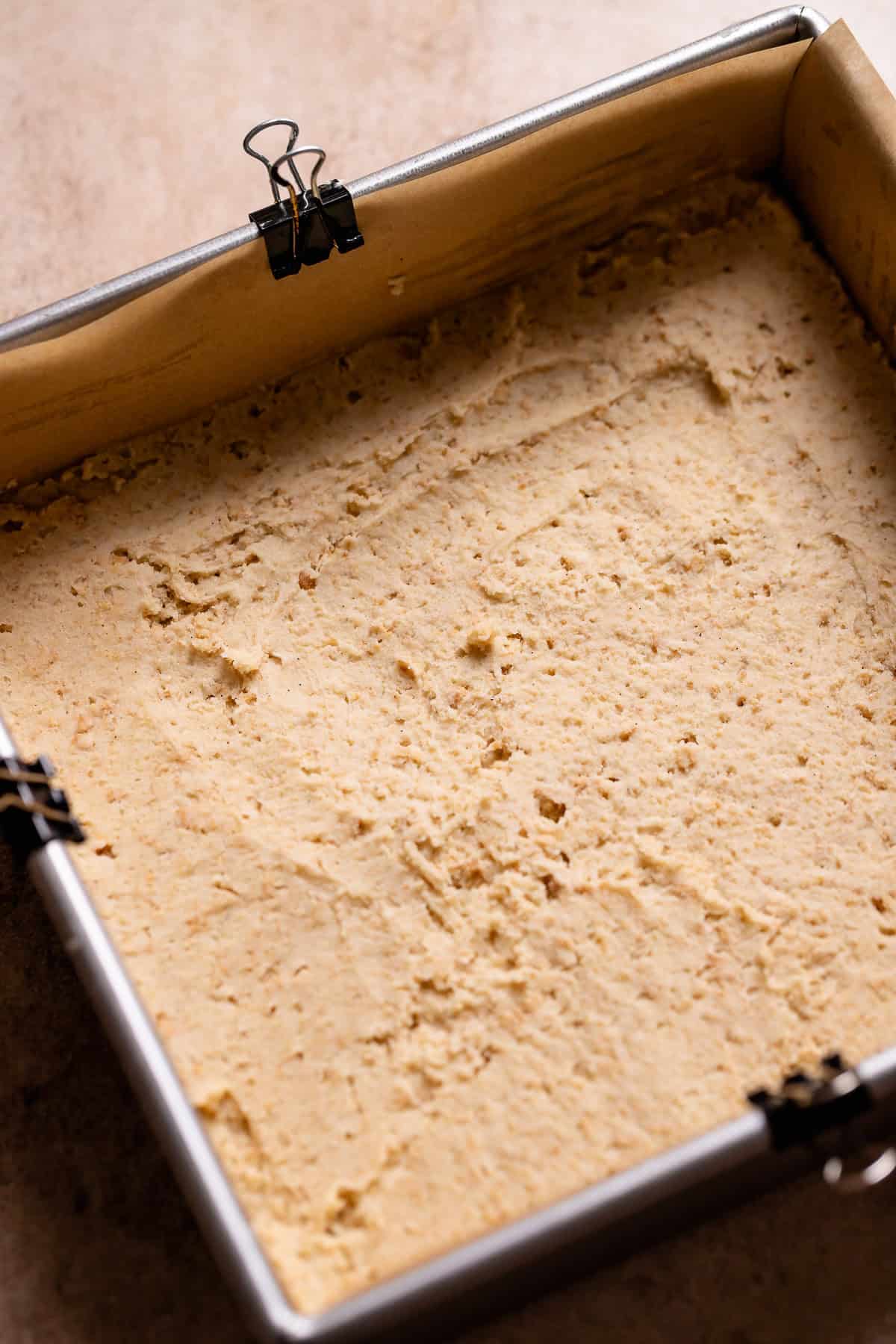 Graham cracker cookie dough spread into the bottom of a metal baking pan.