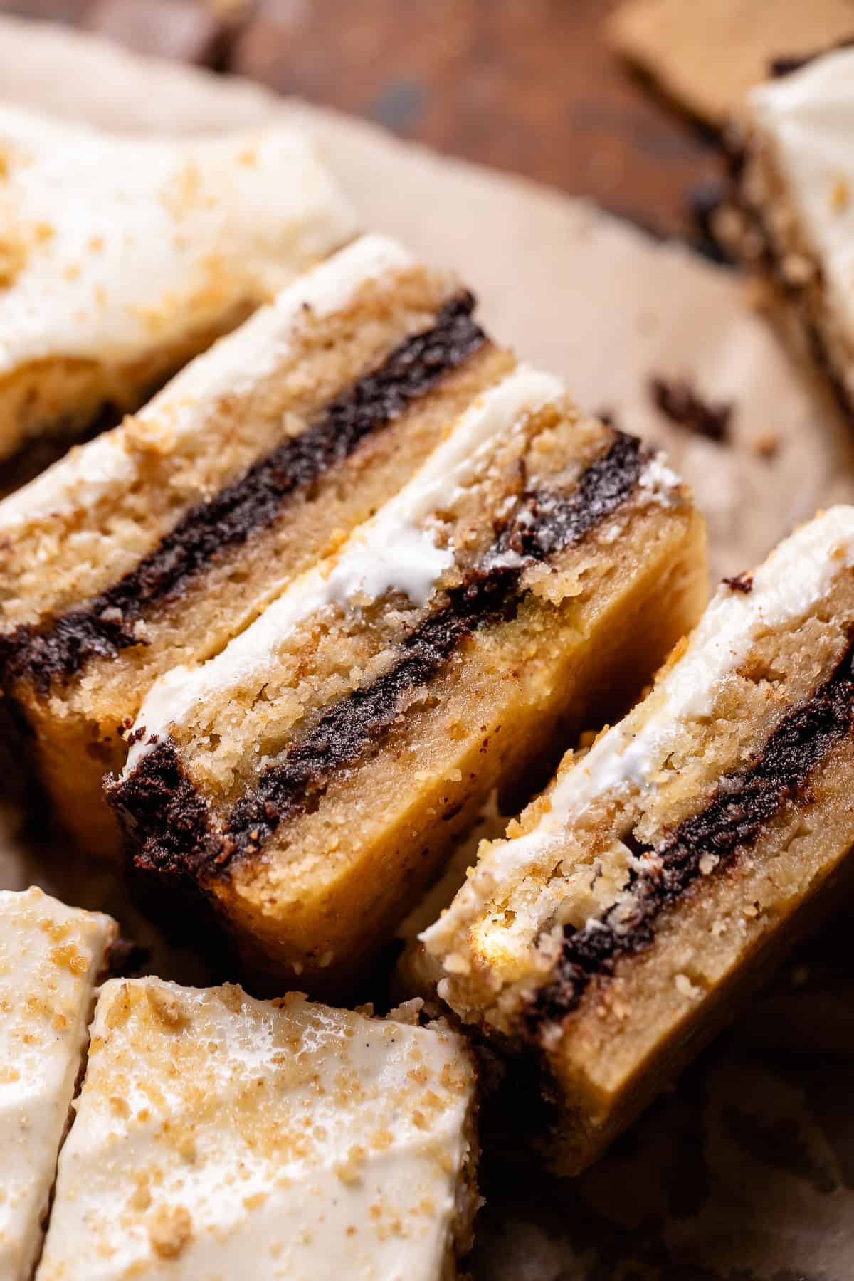 Smores bars on their sides in a row showing the chocolate filling and marshmallow frosting.