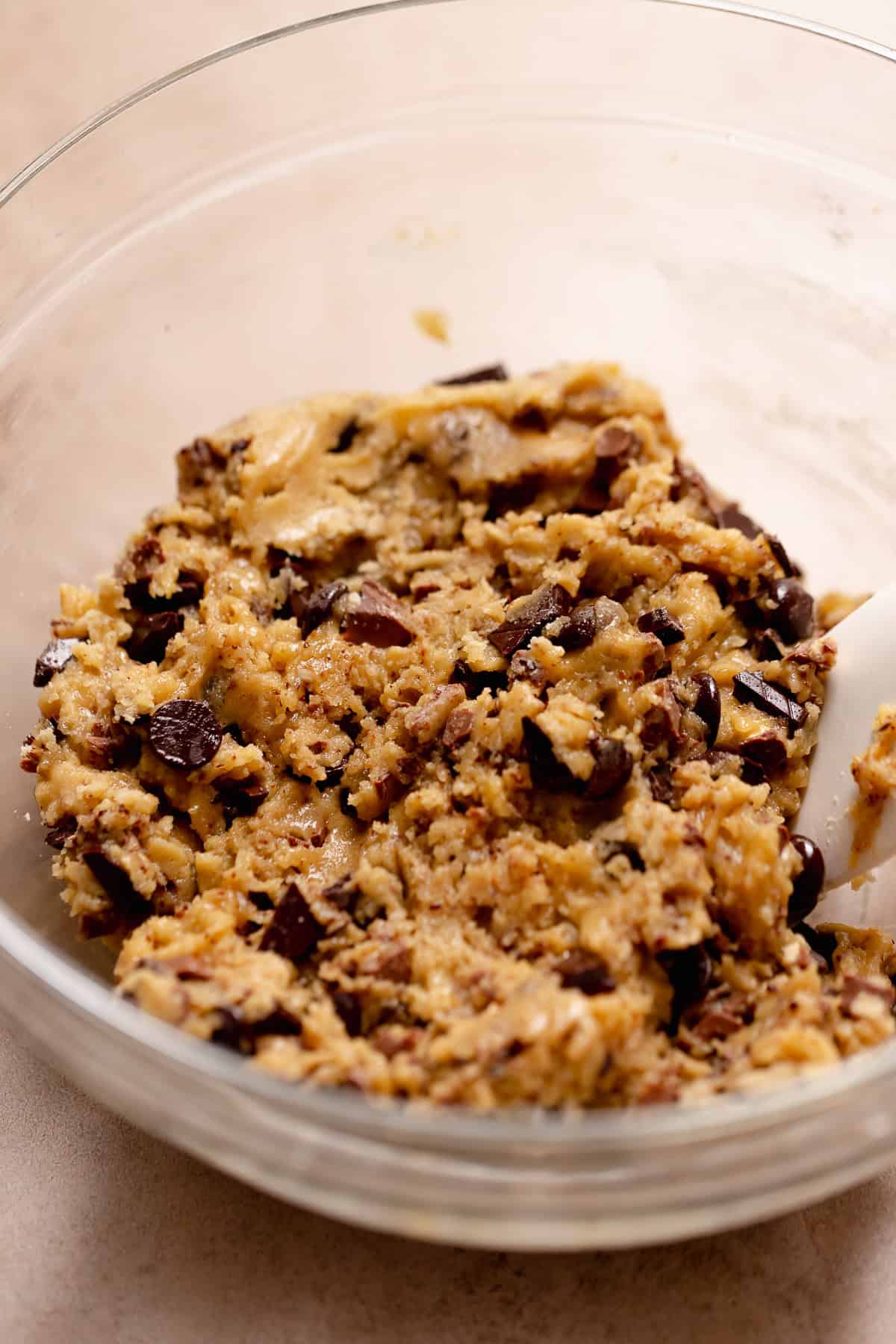 A glass bowl with the brown butter chocolate chip cookie dough in it.