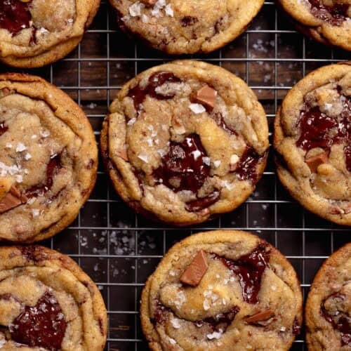 Brown butter chocolate cookies on a wire rack sprinkled with flaky sea salt.