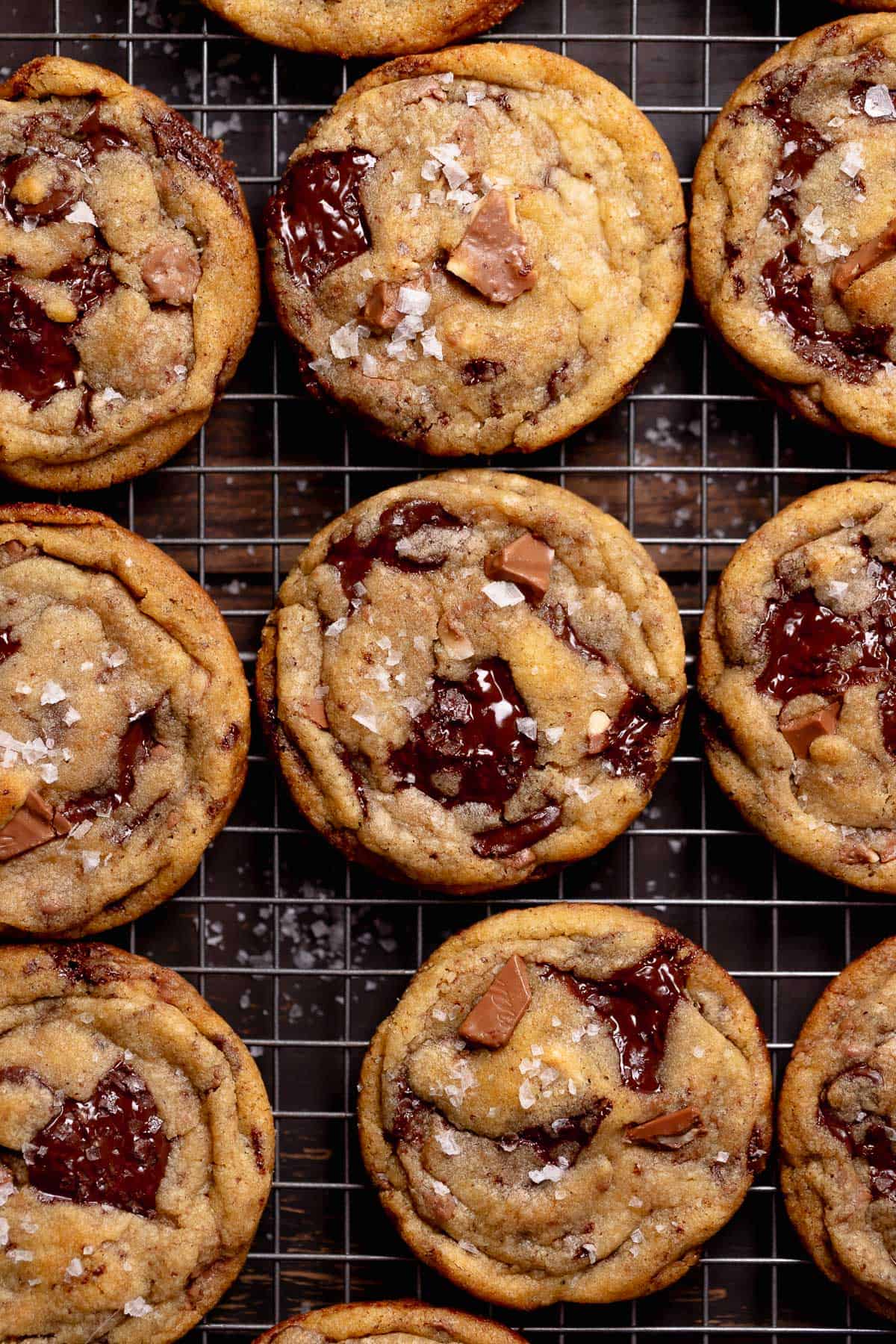 Brown butter chocolate chunk cookies on a wire rack sprinkled with sea salt.