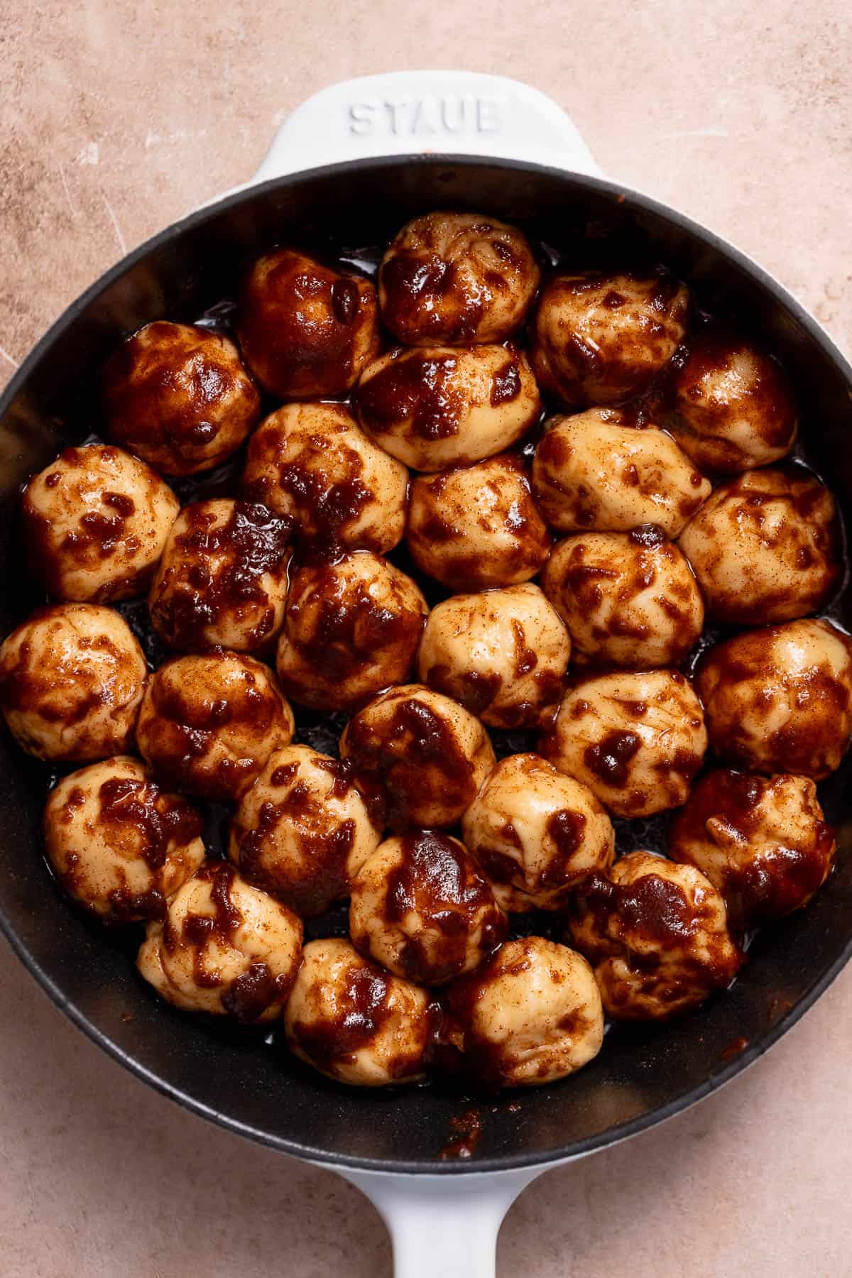 Monkey bread in a skillet covered in melted butter and cinnamon sugar.