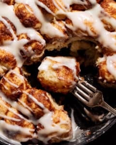 A bite of cinnamon roll monkey bread in a skillet on a fork.