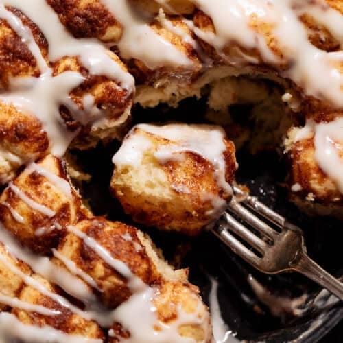 A bite of cinnamon roll monkey bread in a skillet on a fork.