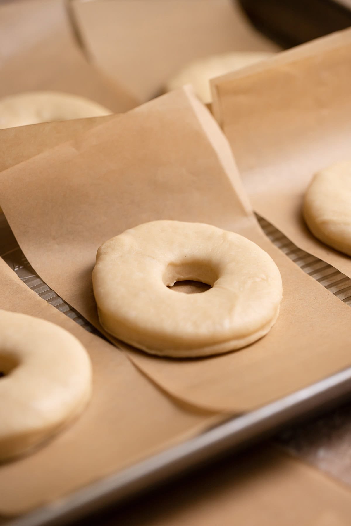 A cut donut on an individual square of parchment paper.