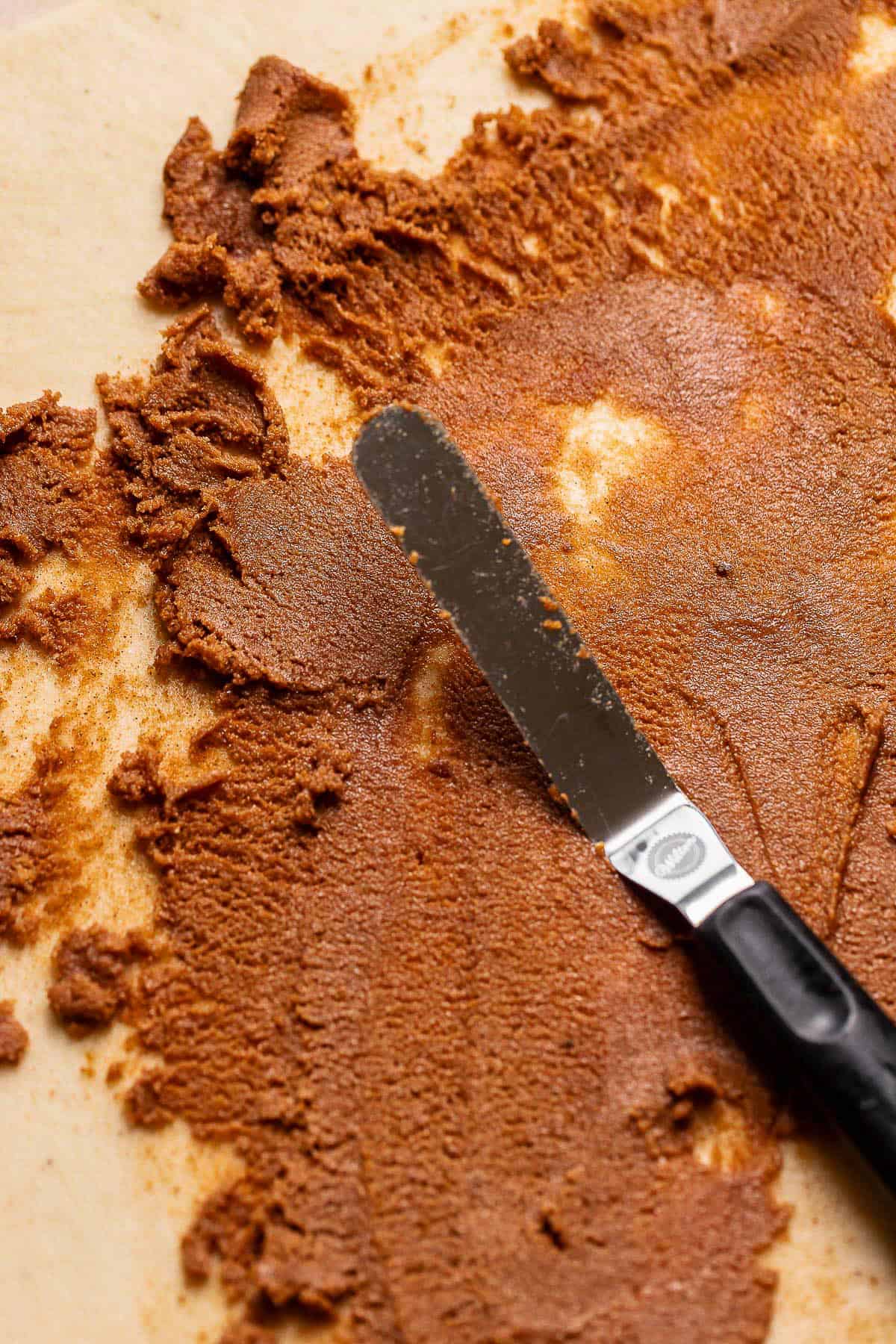 Cinnamon sugar being spread across the cinnamon roll dough.