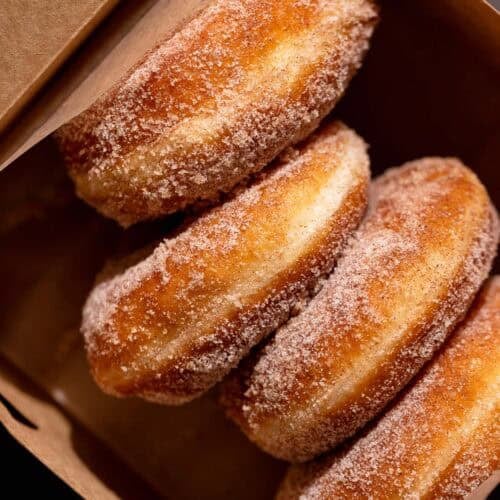 Cinnamon donuts in a brown paper box.