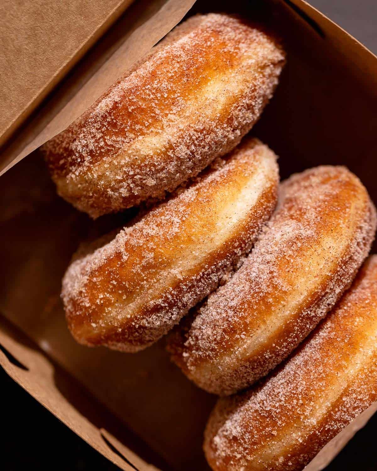 Cinnamon donuts in a brown paper box.