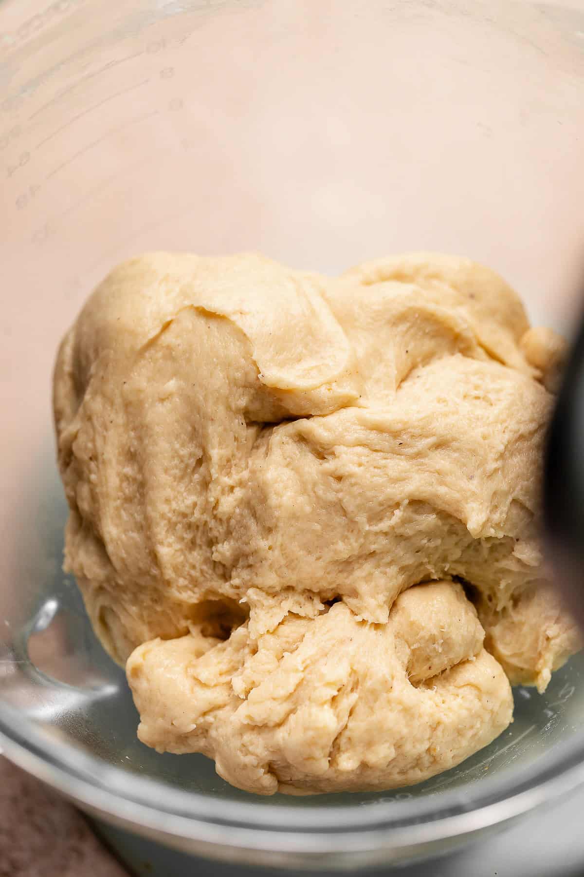 Smooth kneaded cinnamon roll dough in a mixer bowl.