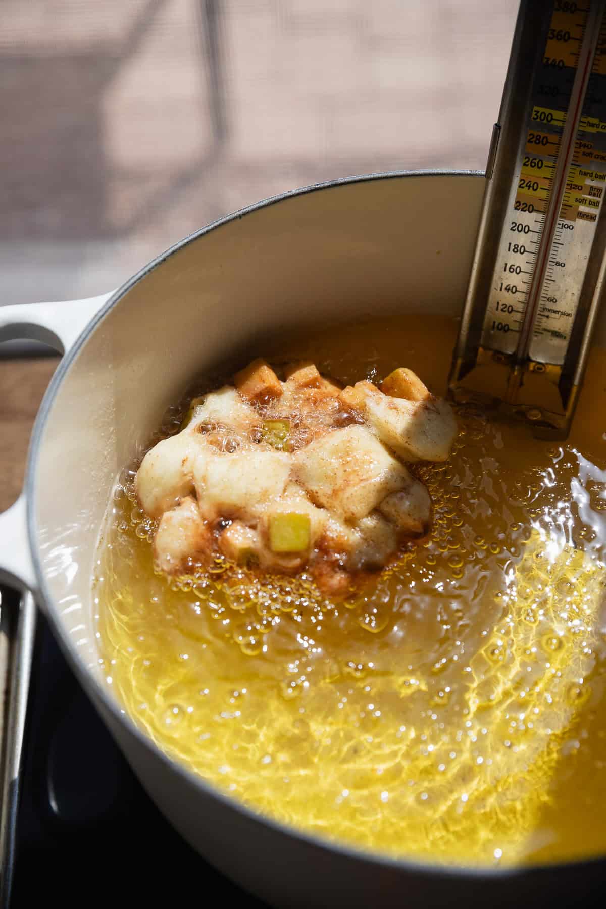 An apple fritter frying in hot oil.