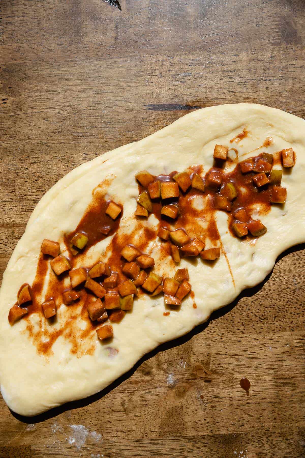 Laying the cinnamon apples on top of the fritter dough.