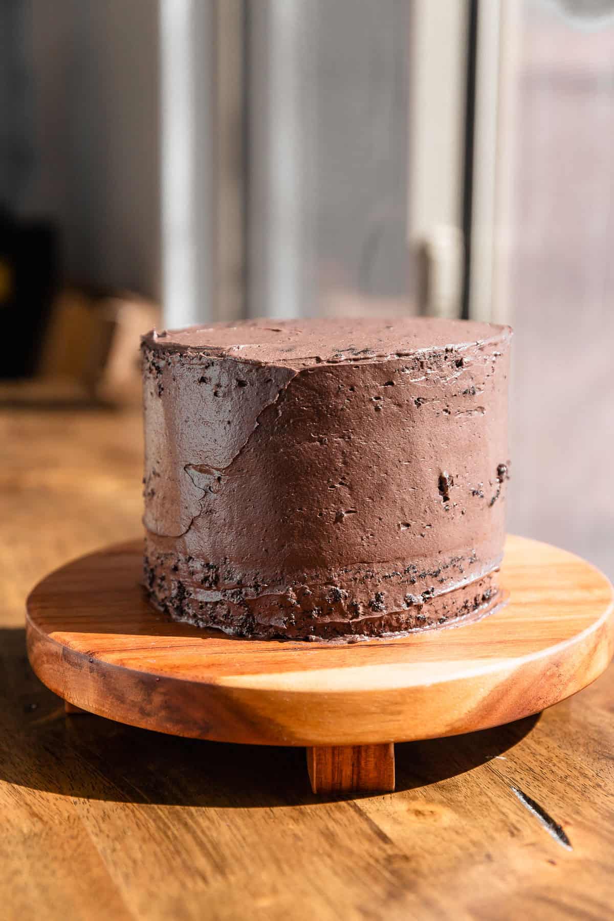 The chocolate cake covered in a crumb coat of black cocoa frosting.