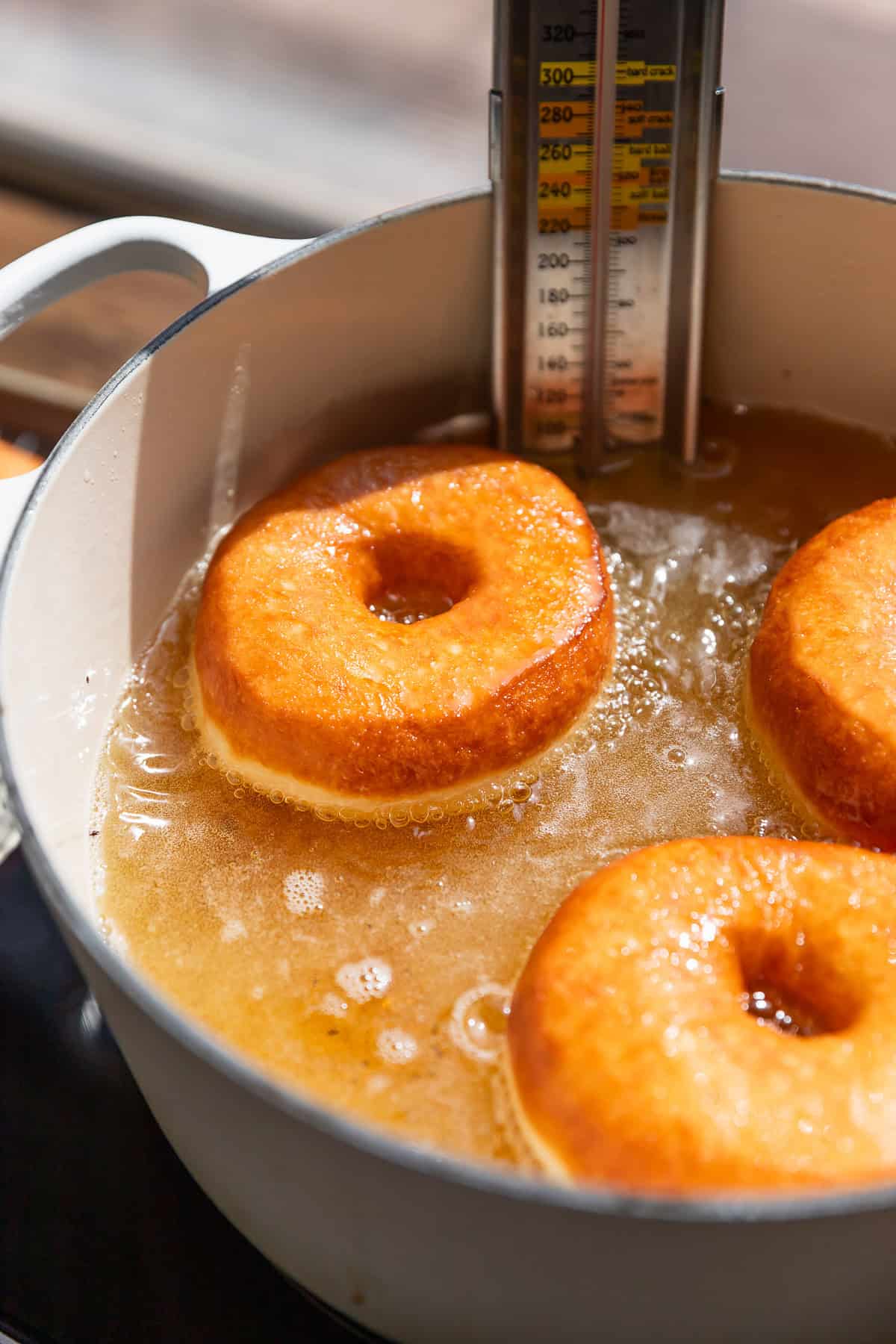 Three donuts frying in hot oil.