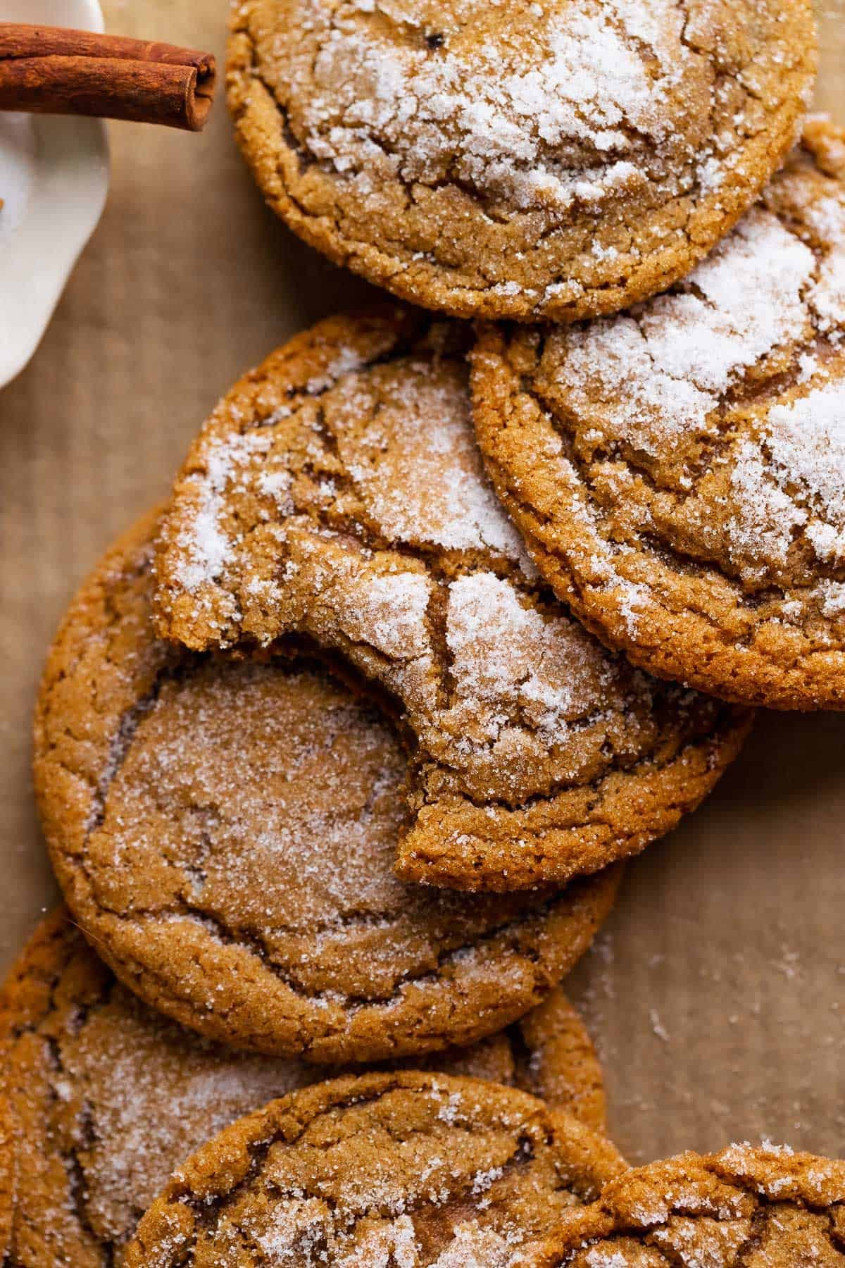 Molasses crinkle cookies in a pile with a bite missing from the center cookie.