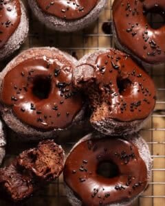 Double chocolate donuts with chocolate frosting and sprinkles on a wire rack.