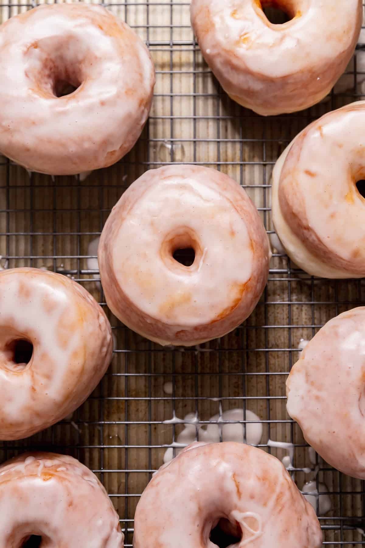 Donuts with vanilla icing sitting on a wire rack.