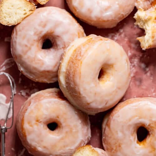 Sugar glazed donuts on pink parchment paper.