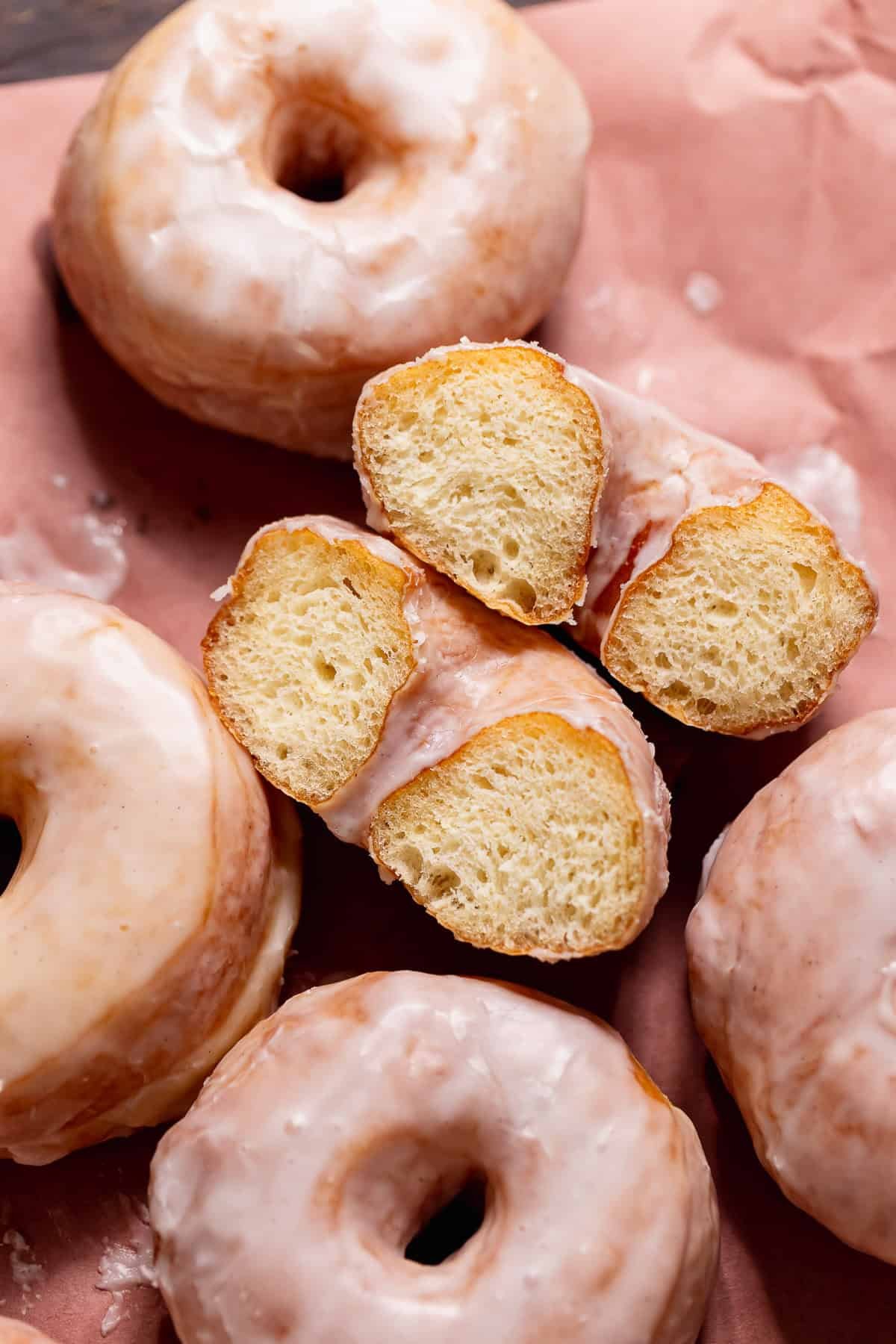 A vanilla glaze donut cut in half on its side showing the soft and fluffy texture.