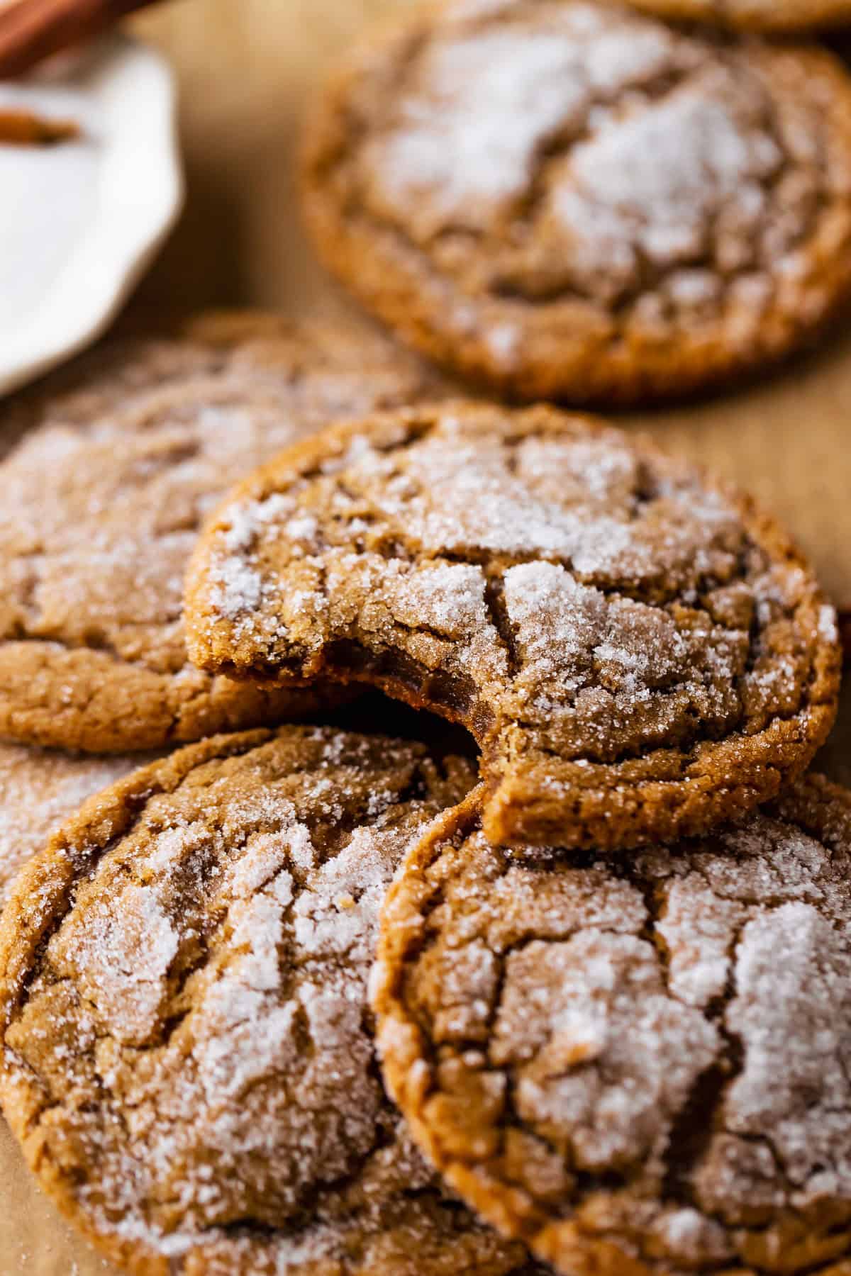 Molasses cookies with crackled sugar tops missing a bite to show the chewy texture.