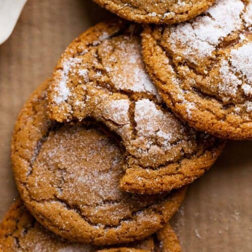 Ginger molasses cookies with crinkle tops on brown parchment paper.