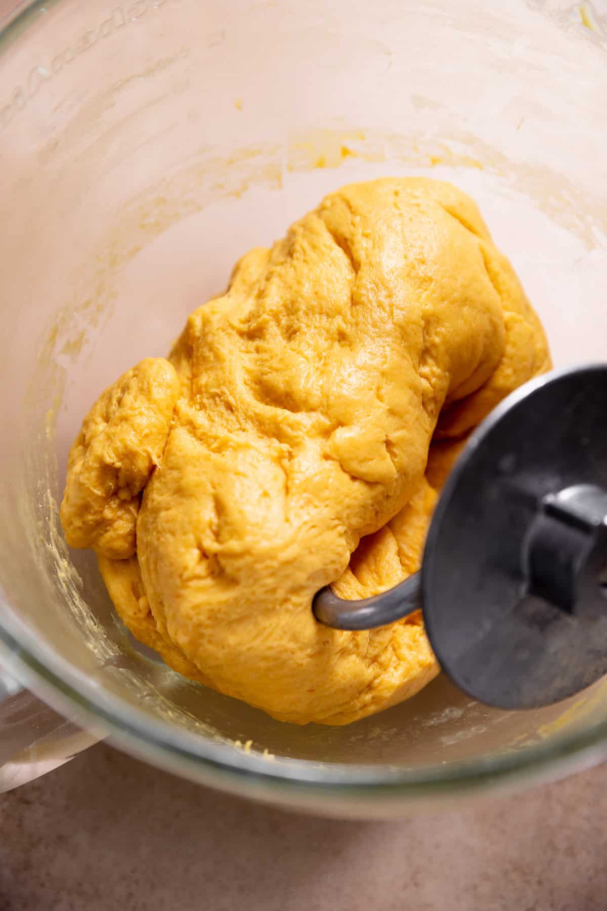 Pumpkin cinnamon roll dough in a glass mixing bowl after kneading.