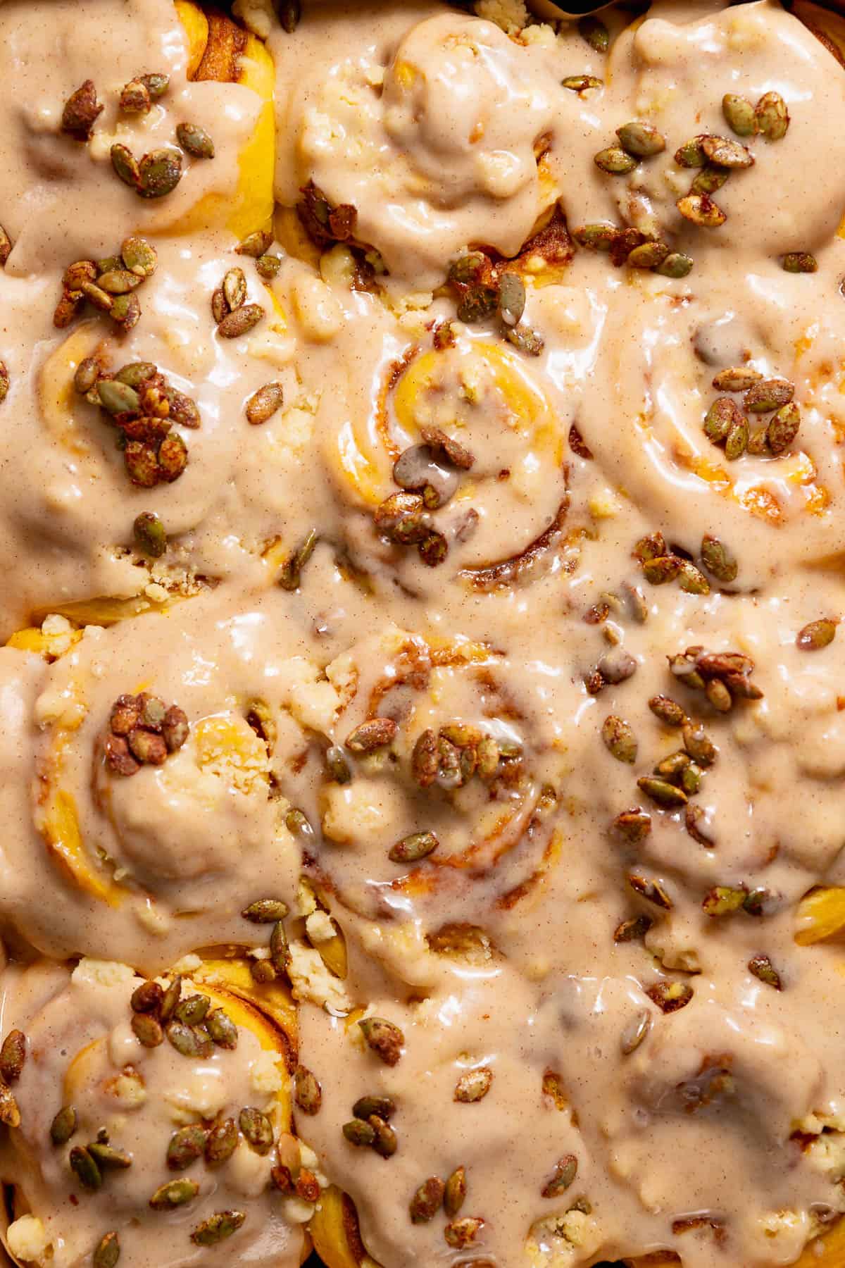 Pumpkin filled cinnamon rolls with cinnamon cream cheese frosting in a baking pan.
