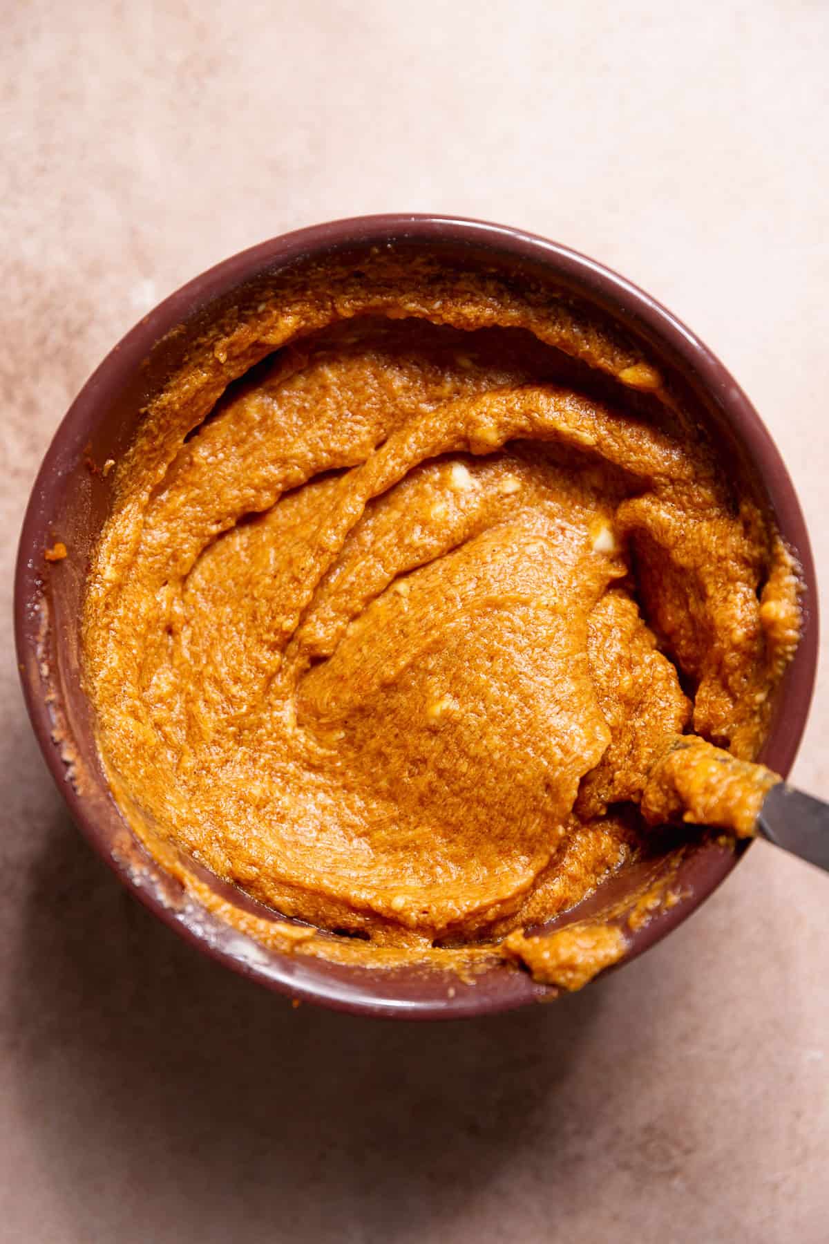 Brown sugar pumpkin pie filling for the cinnamon rolls in a purple bowl.
