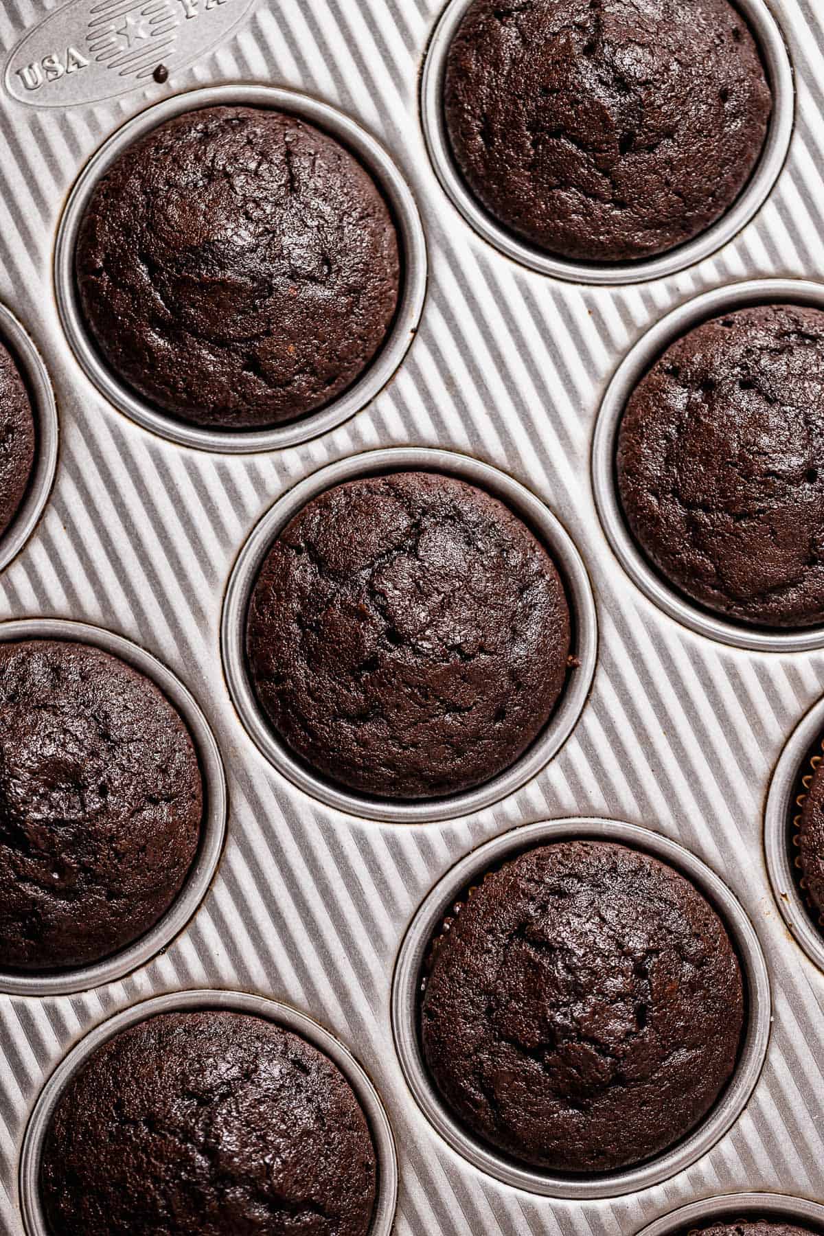 Baked chocolate cupcakes in a baking pan.