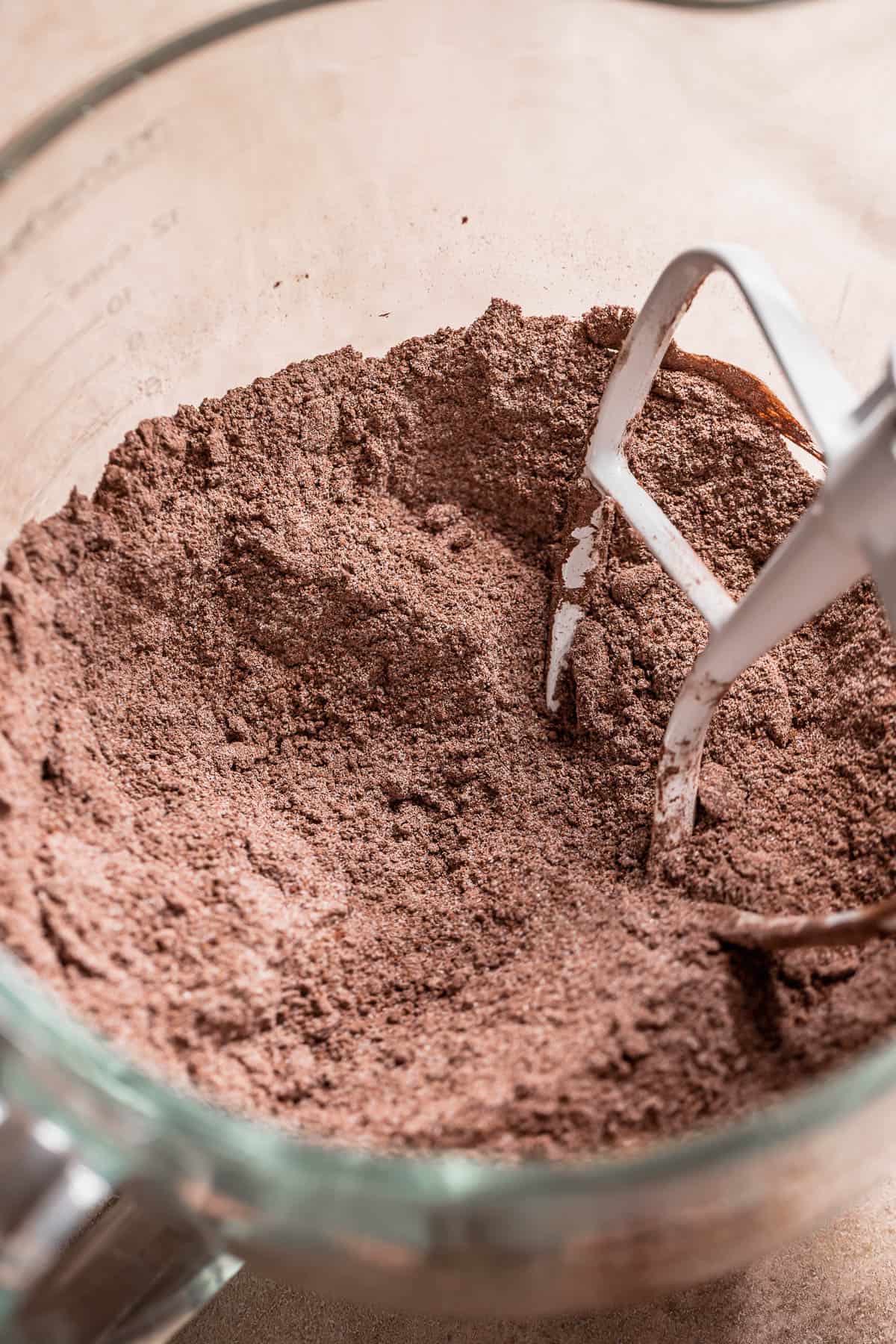 A stand mixer with the dry cupcake ingredients and butter mixed until it looks crumbly.