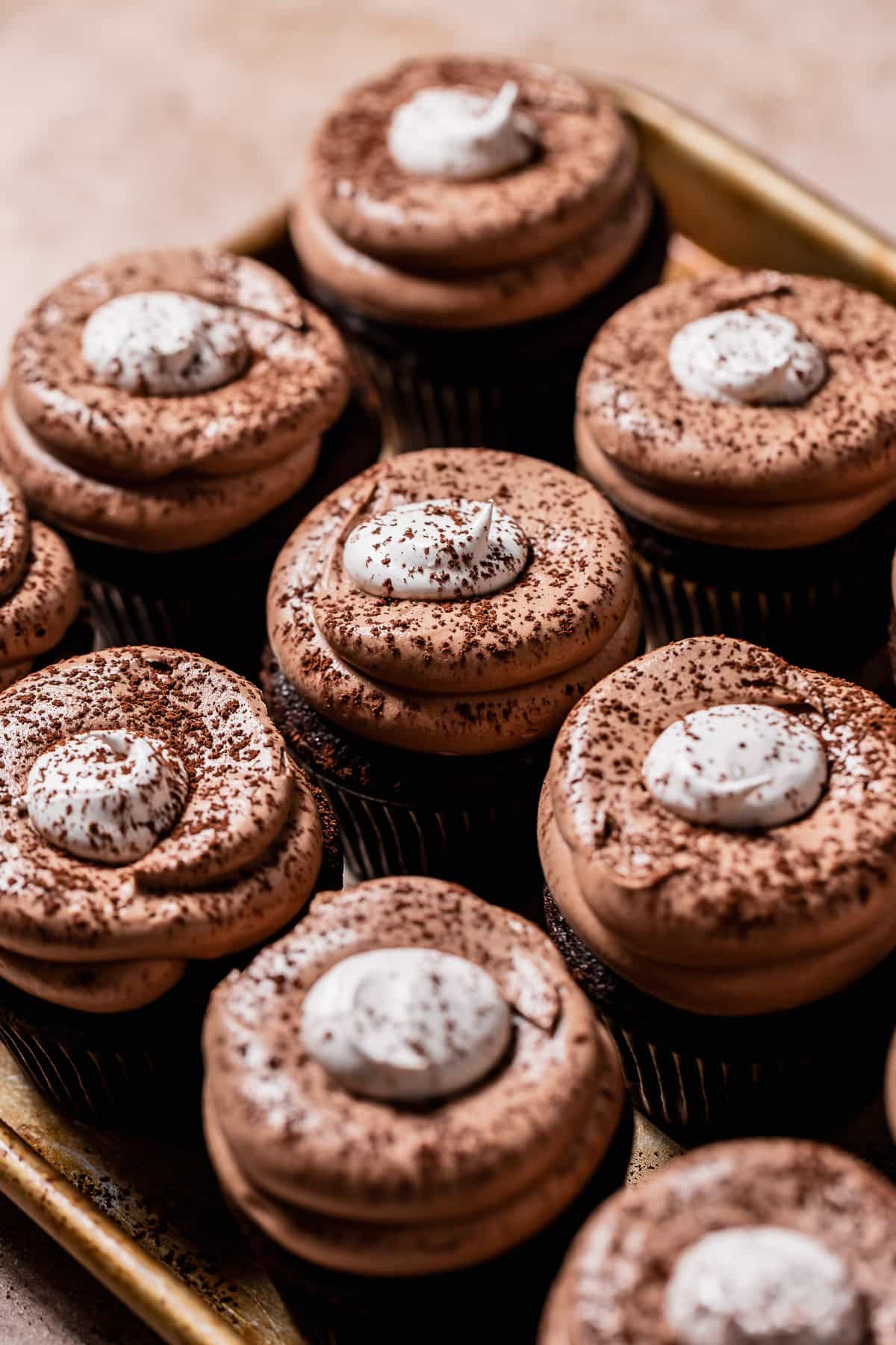 Hot chocolate cupcakes dusted with cocoa powder on a baking tray.