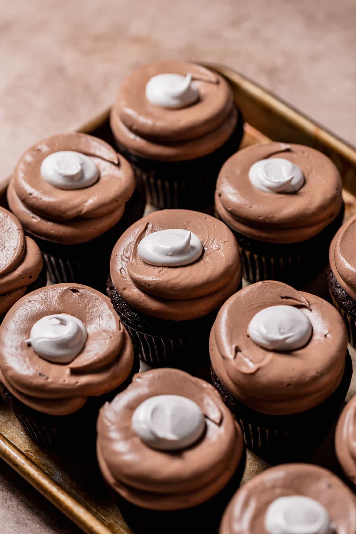 Hot cocoa cupcakes with a ring of milk chocolate frosting and marshmallow fluff in the center.