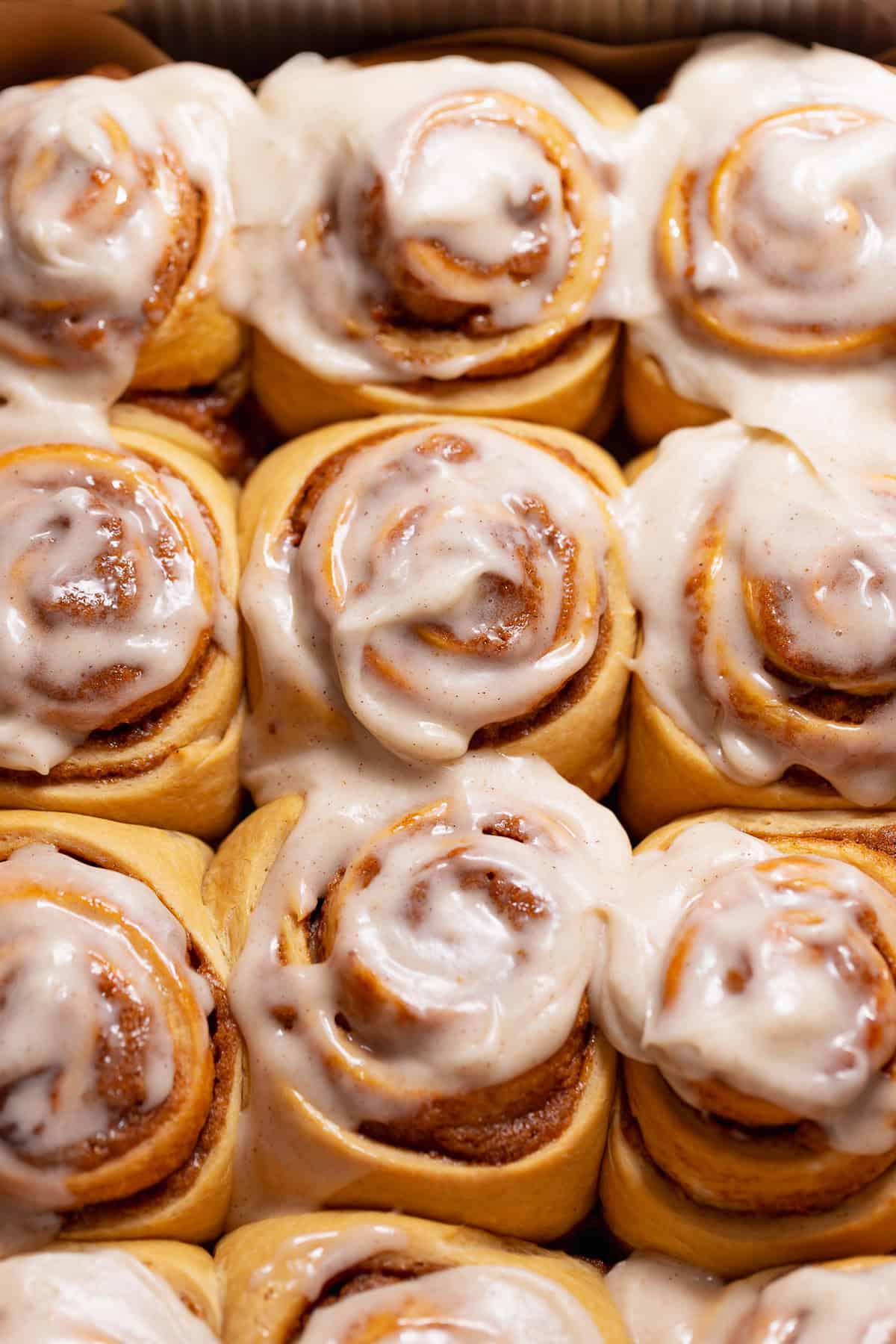 Gingerbread buns with spiced gingerbread cream cheese icing in a baking pan.