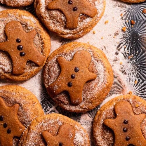 Gingerbread snickerdoodles covered in spiced sugar on a black baking tray.