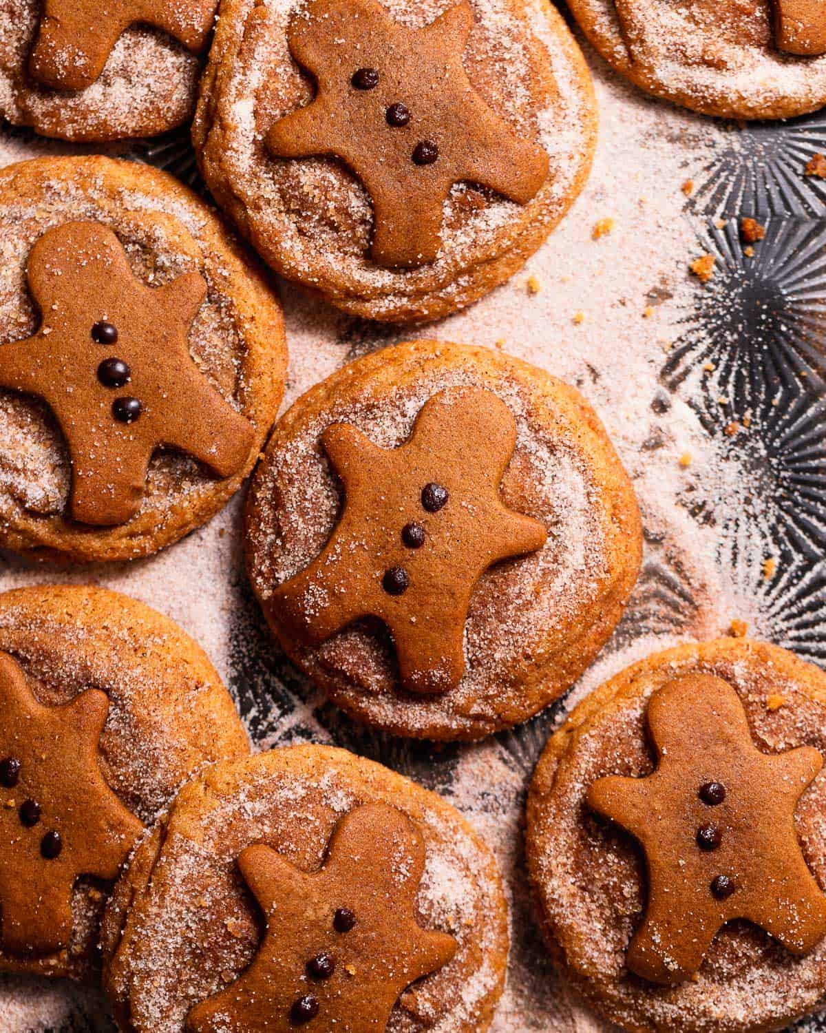Gingerbread snickerdoodles covered in spiced sugar on a black baking tray.