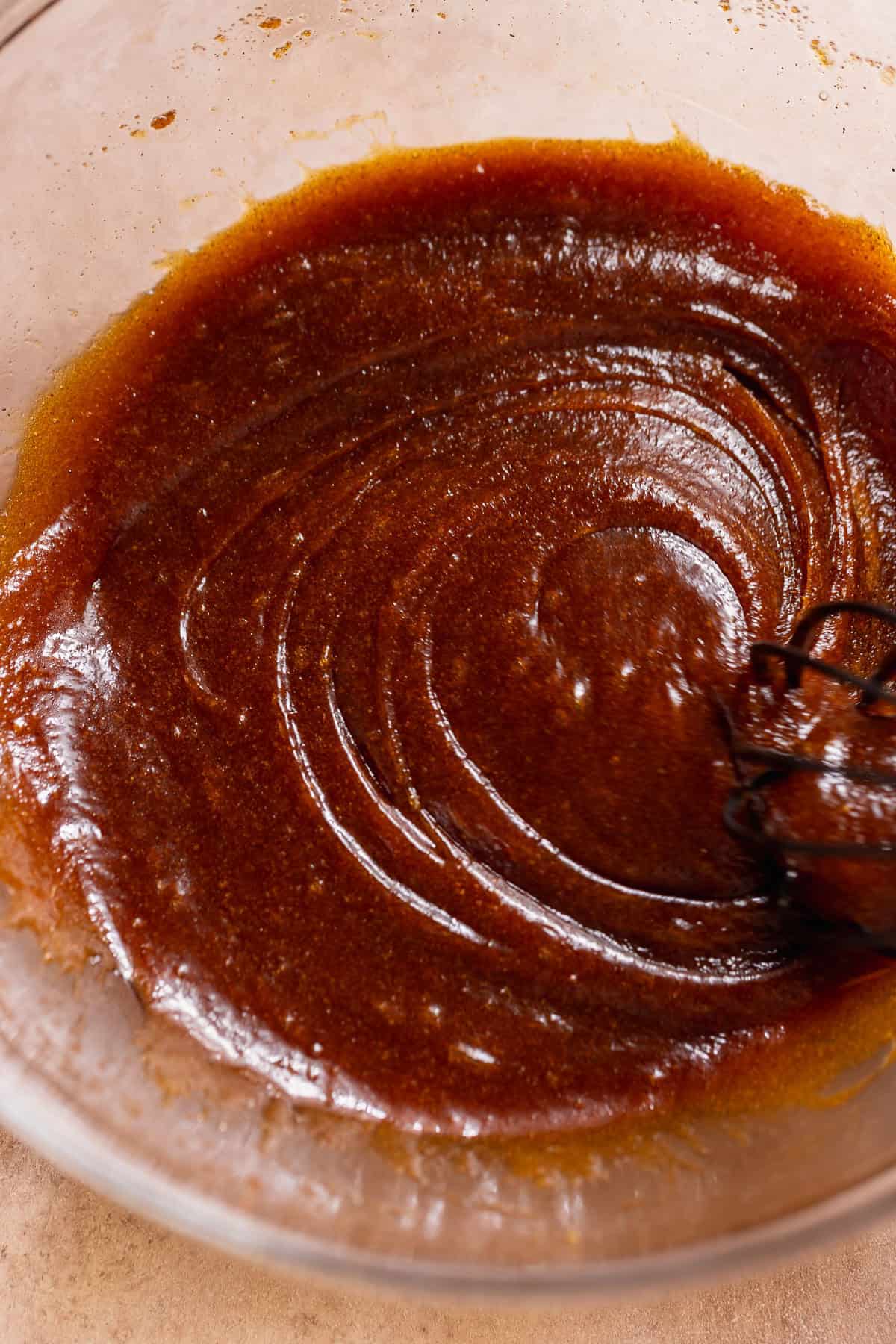 Wet ingredients whisked in a glass bowl.