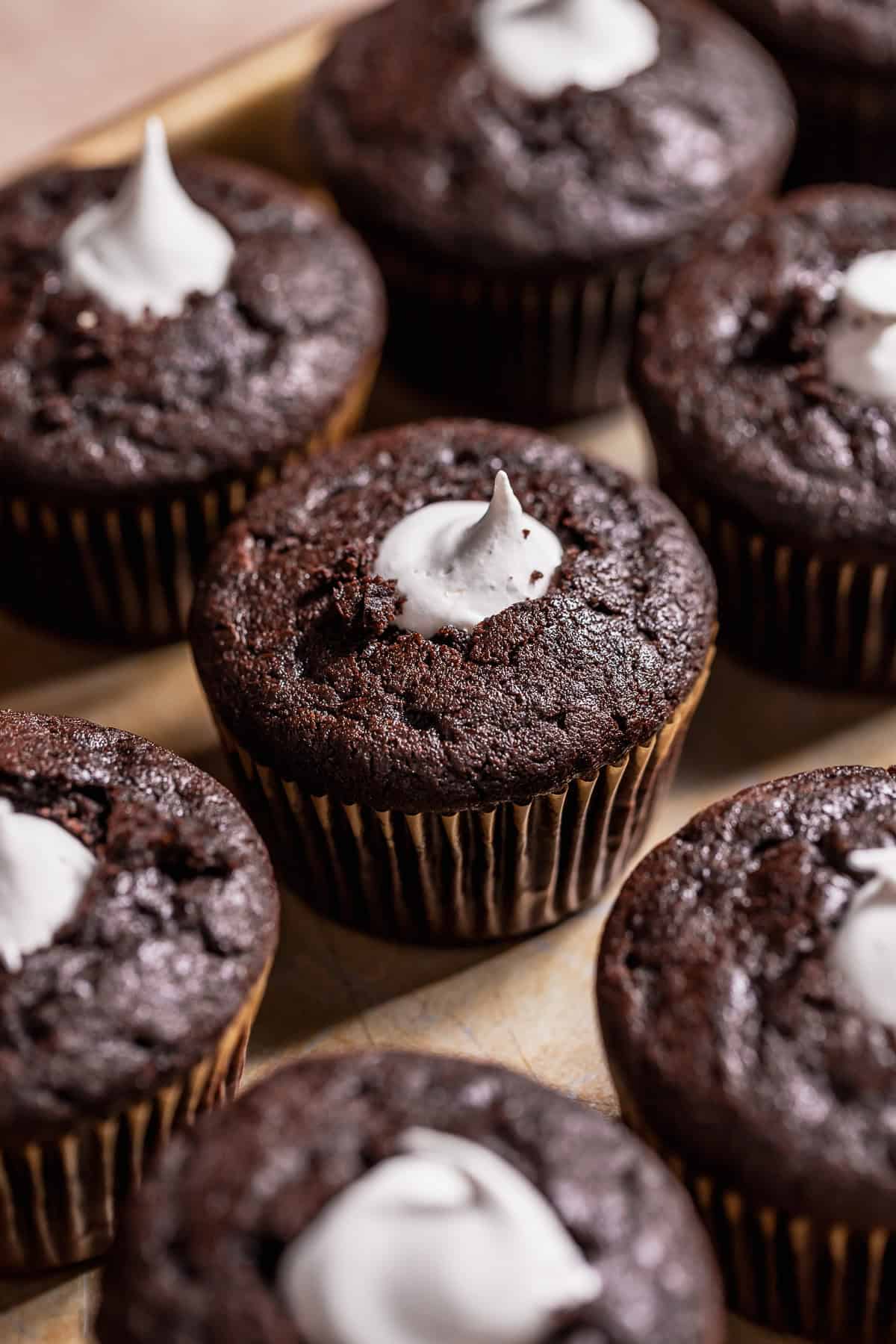 Chocolate cupcakes with marshmallow filling on a baking sheet.